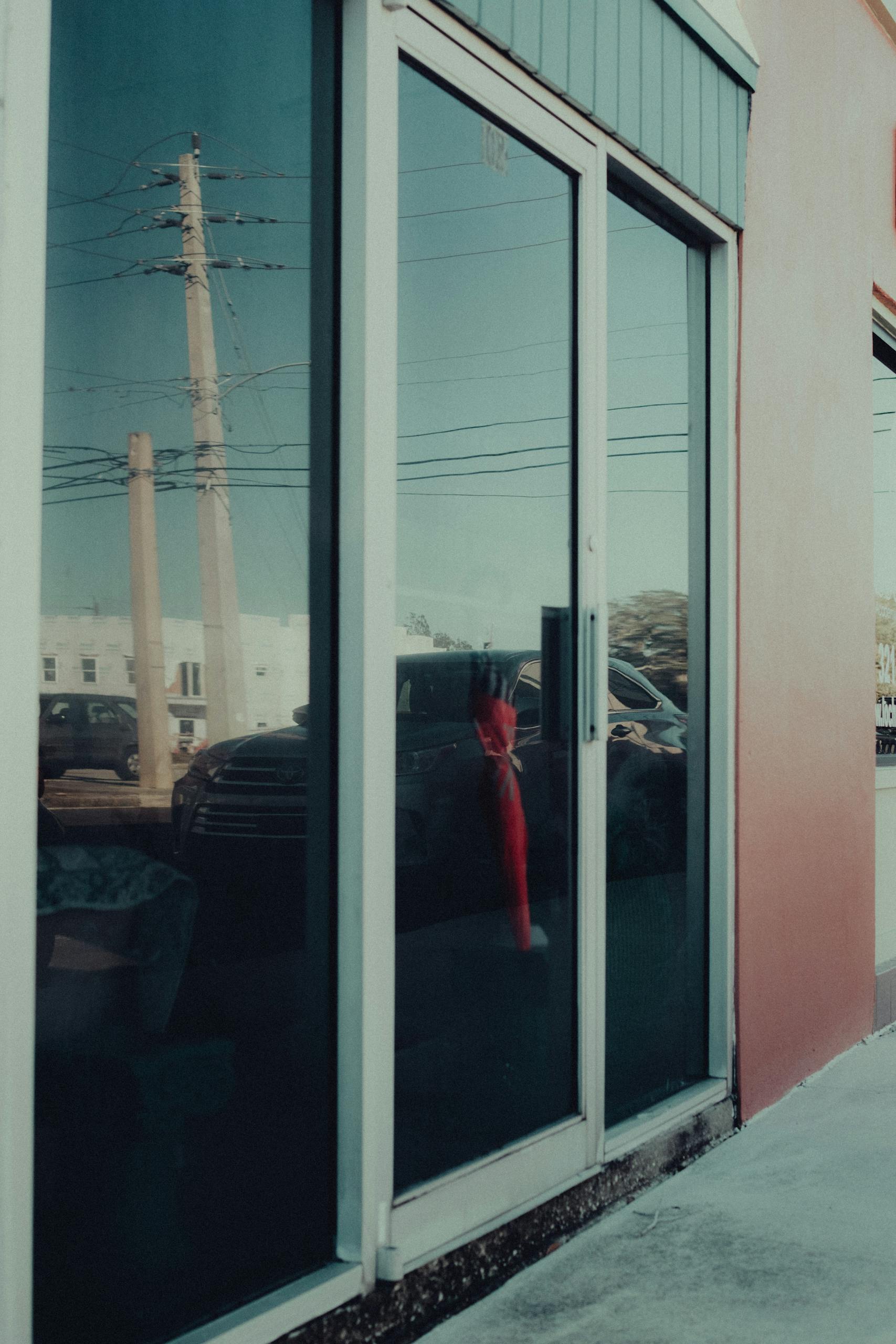 Street view of a building with reflections in glass windows capturing urban life.